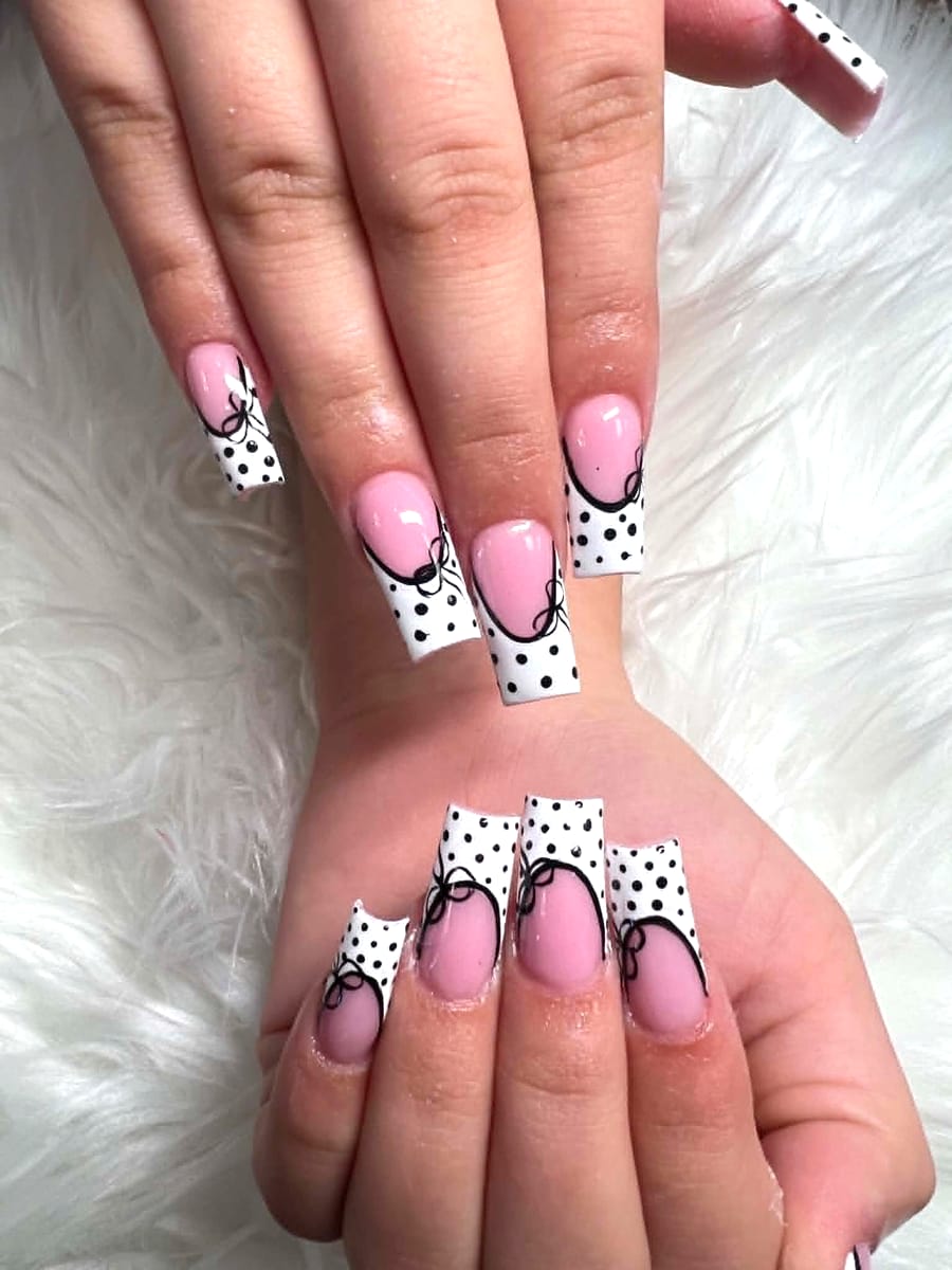 Soft pink square nails with white-and-black polka-dot tips and ribbon bow line art
