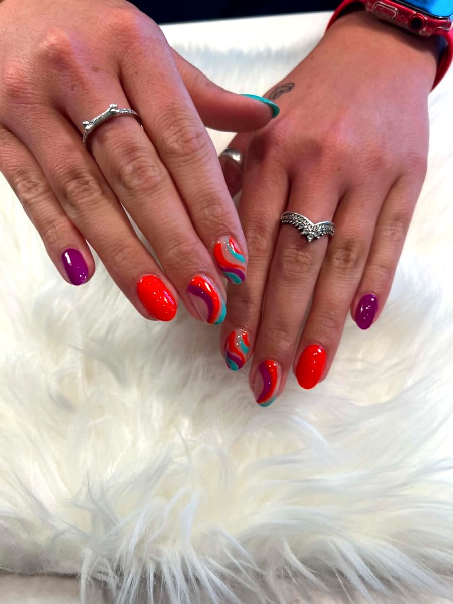 Bright orange, purple, and teal swirl nail art on short almond nails
